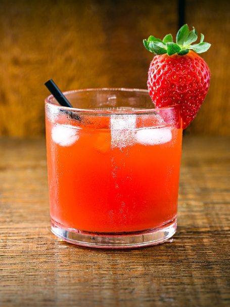 Recette de Cocktail caïpi fraise à base de Cachaça et de sirop de canne servi dans un verre décoré avec une fraise.