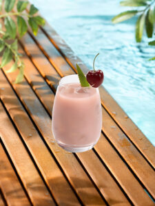 Cocktail smoothie pinky dans un verre avec glaçons et cerise entière