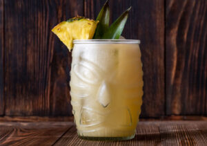 Cocktail tiki dans un verre sculptée avec visage traditionnel tiki et tranche d'ananas