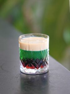 Cocktail after eight, un shot composé de crème de cacao, de crème de menthe et de crème à la vanille, créant une belle superposition de couleurs sombres et fraîches