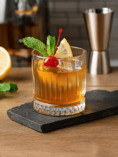 Cocktail la Modernista servi dans un verre à whisky et décoré avec des feuilles de menthe