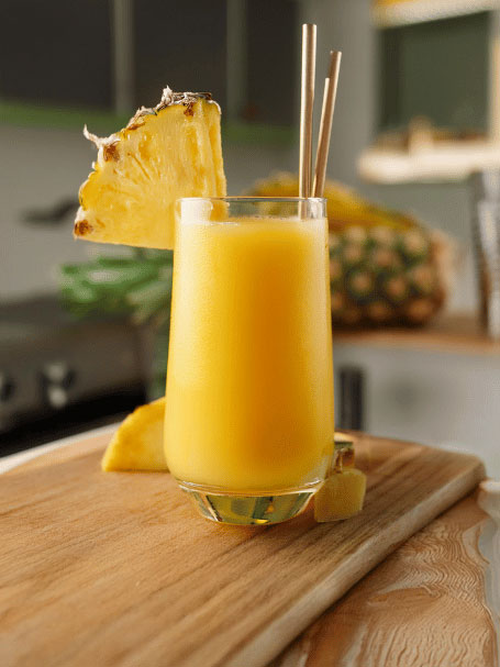 Cocktail Passion Tropicale, recette sans alcool avec des fruits exotiques, servi dans un verre décoré par une tranche d'ananas.